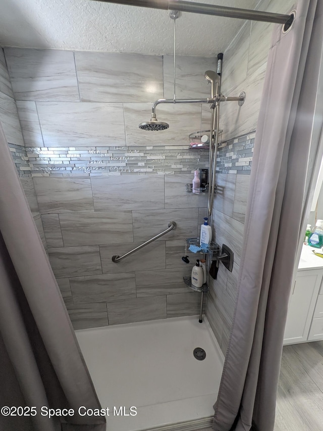 bathroom with a textured ceiling and a tile shower