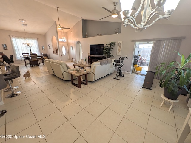 living area featuring high vaulted ceiling, arched walkways, light tile patterned flooring, and ceiling fan with notable chandelier