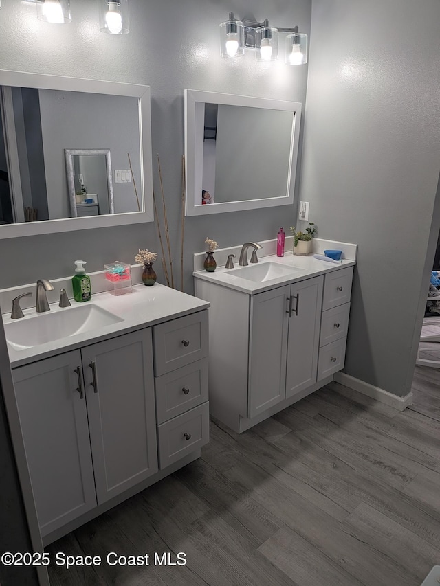 bathroom with wood finished floors, two vanities, and a sink