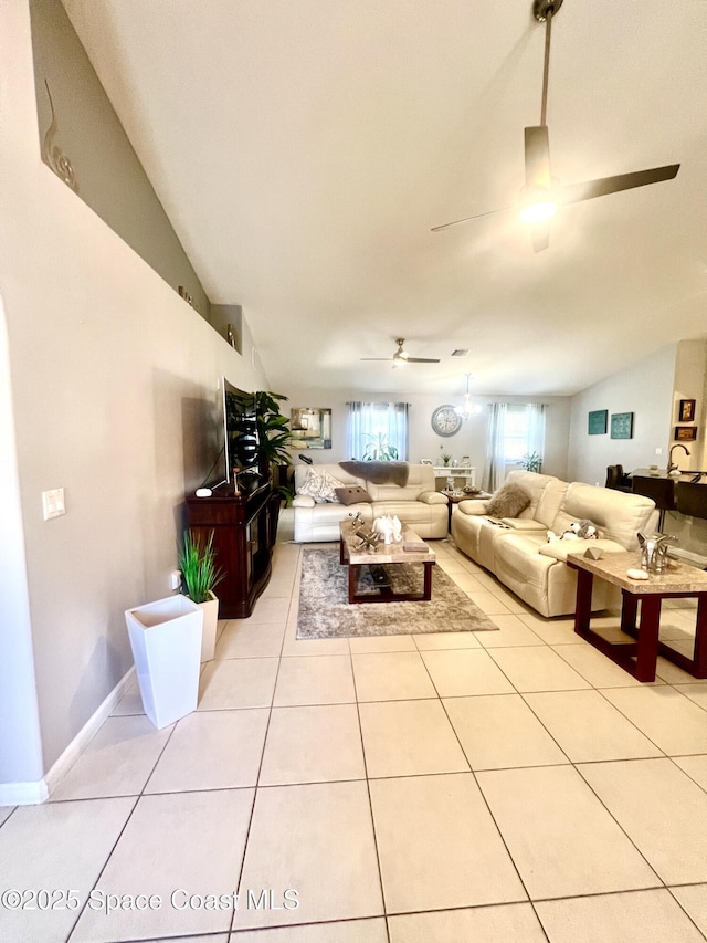 living area with light tile patterned floors, lofted ceiling, a ceiling fan, and baseboards