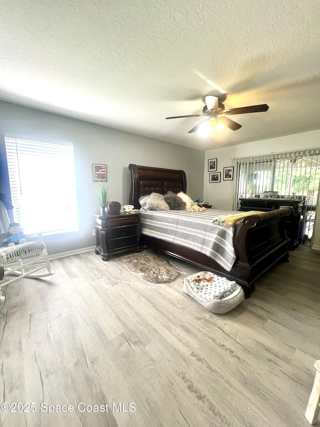 bedroom with ceiling fan, a textured ceiling, wood finished floors, and baseboards