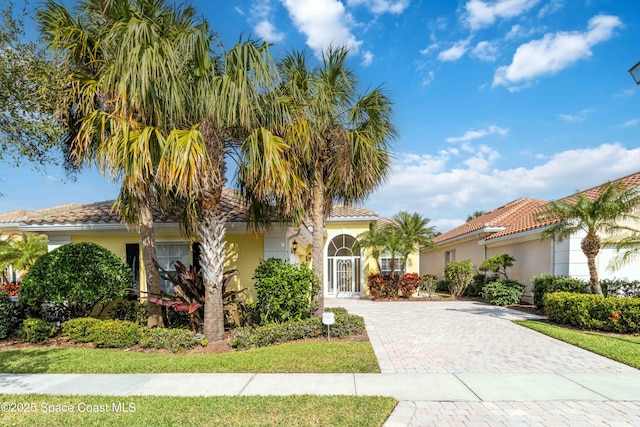 view of front facade with decorative driveway, a tile roof, and stucco siding