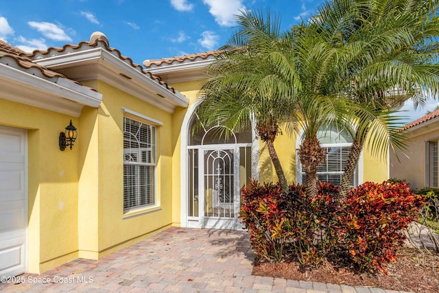 view of exterior entry with a tile roof and stucco siding