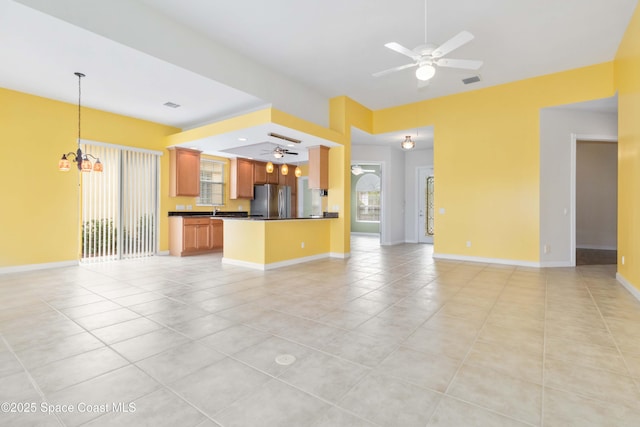 unfurnished living room featuring light tile patterned floors, visible vents, baseboards, and ceiling fan with notable chandelier