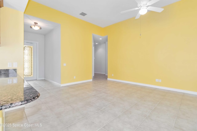 spare room featuring a ceiling fan, baseboards, and light tile patterned floors