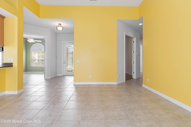 unfurnished room with light tile patterned floors, a ceiling fan, and baseboards