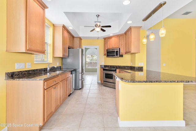 kitchen featuring stainless steel appliances, a peninsula, a sink, a ceiling fan, and a raised ceiling