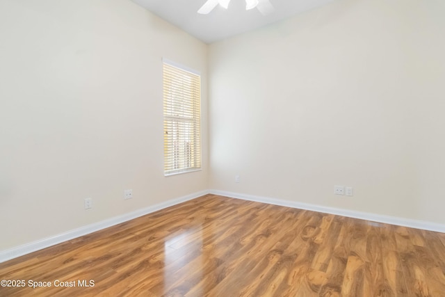 empty room with ceiling fan, wood finished floors, and baseboards