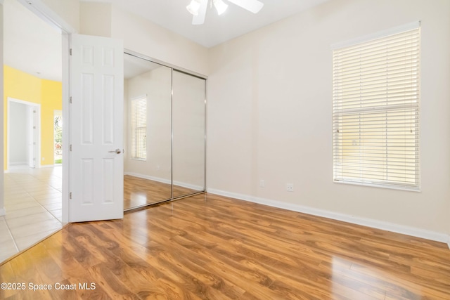 unfurnished bedroom featuring a closet, wood finished floors, and baseboards