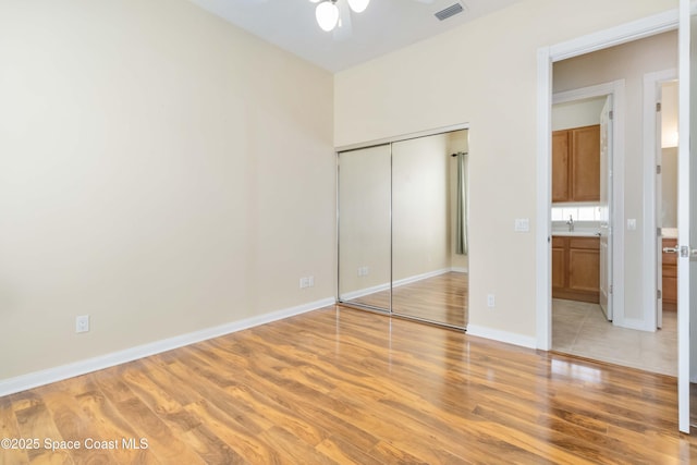 unfurnished bedroom featuring a sink, visible vents, baseboards, a closet, and light wood-type flooring