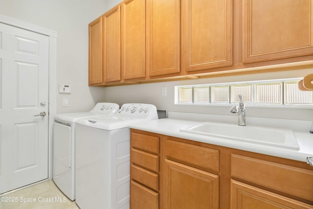 laundry room featuring washing machine and dryer, cabinet space, and a sink