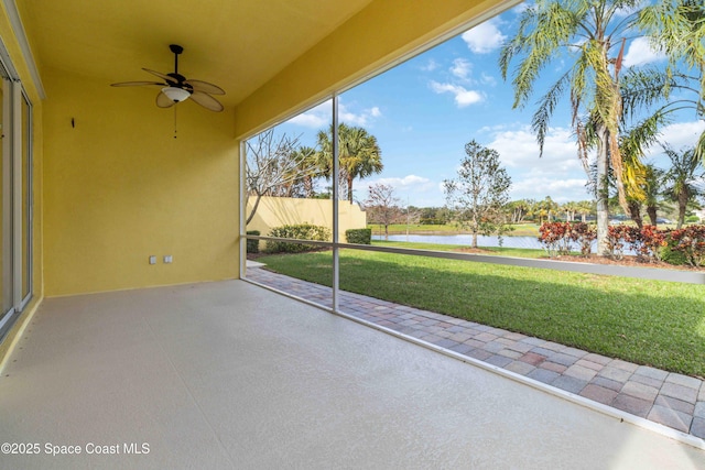 unfurnished sunroom with a ceiling fan, a water view, and plenty of natural light