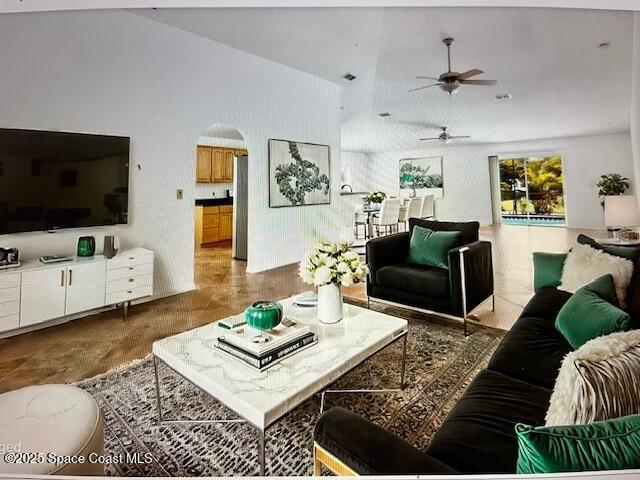 living area with ceiling fan, a high ceiling, and arched walkways