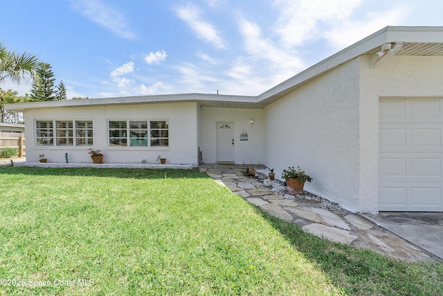 112 Sunset Dr, Cocoa Beach, FL 32931 - entrance to property featuring stucco siding, a yard, and an attached garage
