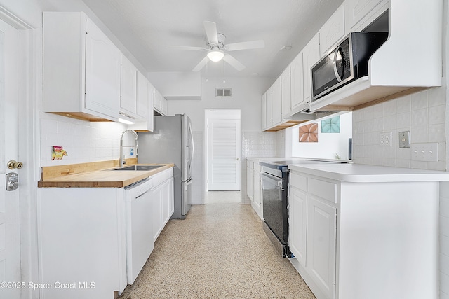 112 Sunset Dr, Cocoa Beach, FL 32931 - kitchen with a sink, stainless steel appliances, a ceiling fan, tasteful backsplash, and dark speckled floor