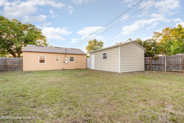 rear view of house with a fenced backyard, a lawn, and an outbuilding