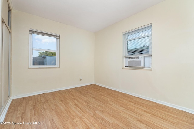 unfurnished room featuring cooling unit, baseboards, and light wood-style flooring