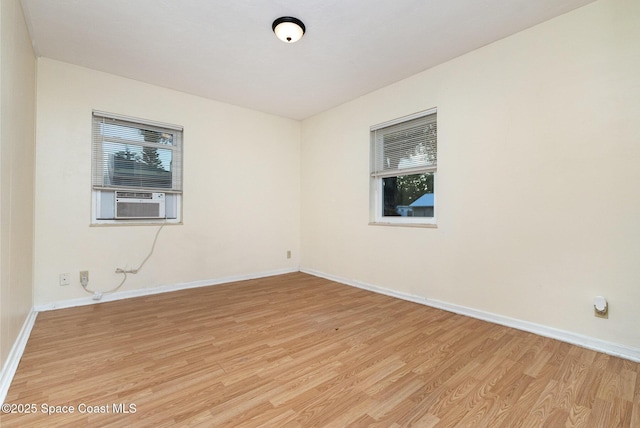 empty room with light wood-style flooring, cooling unit, and baseboards