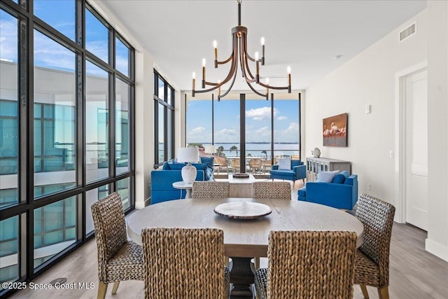 225 Strand Dr Unit 401, Melbourne Beach, FL 32951 - dining space featuring a notable chandelier, wood finished floors, visible vents, and expansive windows
