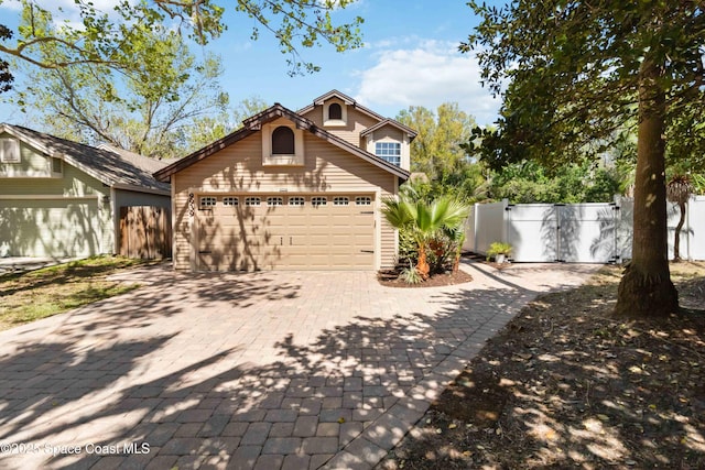 view of front of house with a gate, decorative driveway, fence, and an attached garage