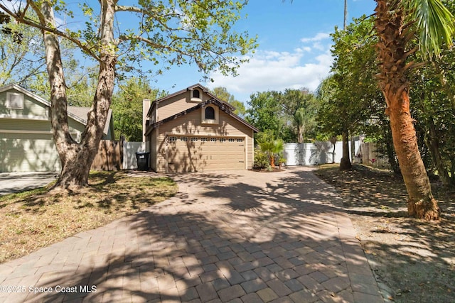 view of front facade with driveway, a garage, and fence