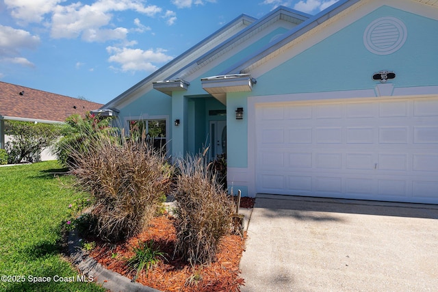 view of front facade featuring a front yard, driveway, an attached garage, and stucco siding