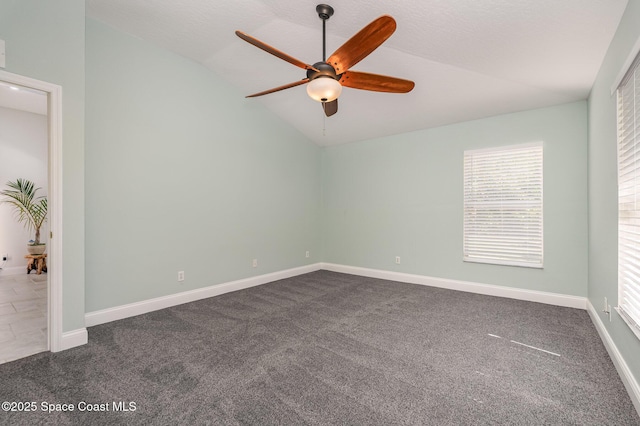 empty room with a ceiling fan, lofted ceiling, baseboards, and dark colored carpet