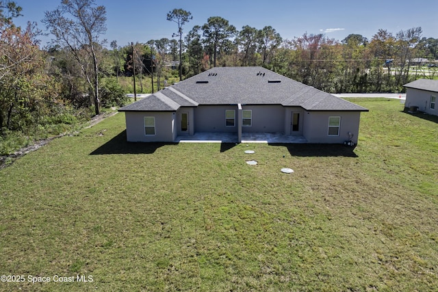 back of property featuring a patio area, roof with shingles, a lawn, and stucco siding