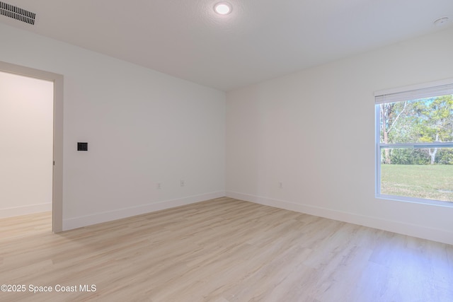 unfurnished room featuring light wood finished floors, baseboards, and visible vents