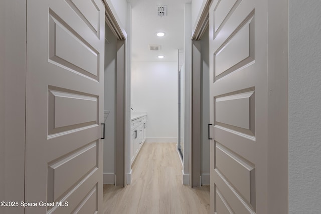 hallway featuring baseboards, light wood-type flooring, visible vents, and recessed lighting