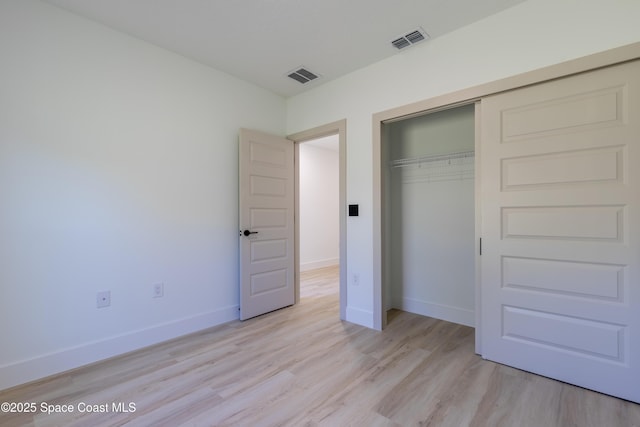 unfurnished bedroom featuring light wood-style flooring, a closet, visible vents, and baseboards