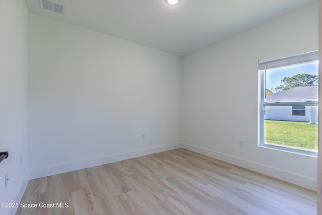 spare room with light wood-style floors, visible vents, and baseboards