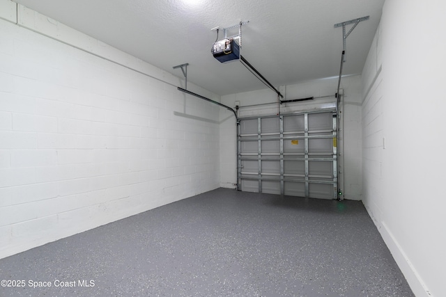 garage with a garage door opener and concrete block wall