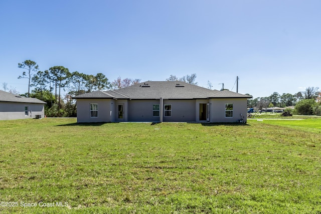 back of property featuring a lawn and stucco siding