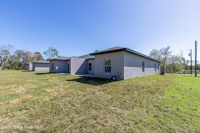 back of property with central AC unit, a lawn, and stucco siding