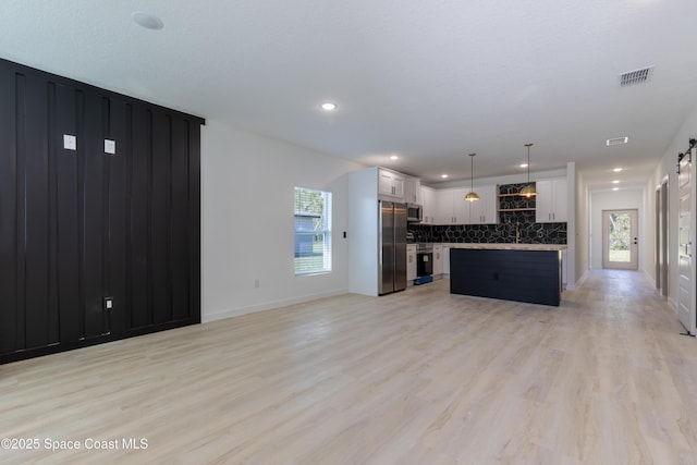 kitchen with visible vents, decorative backsplash, light wood-style flooring, appliances with stainless steel finishes, and light countertops