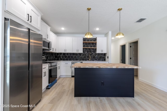 kitchen featuring butcher block countertops, appliances with stainless steel finishes, a sink, open shelves, and backsplash