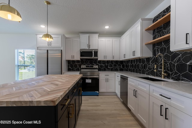 kitchen featuring wood counters, appliances with stainless steel finishes, white cabinetry, open shelves, and a sink