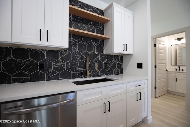 kitchen with dishwasher, light wood-style flooring, a sink, and open shelves