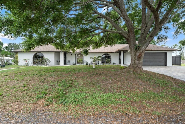 single story home featuring an attached garage, stucco siding, concrete driveway, and a front yard