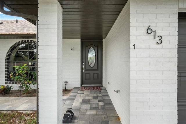 property entrance with roof with shingles and brick siding