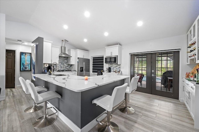 kitchen with a peninsula, tasteful backsplash, appliances with stainless steel finishes, and lofted ceiling