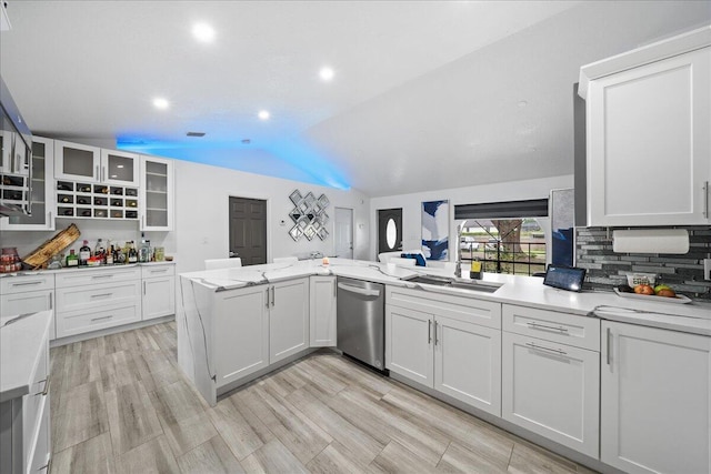 kitchen with glass insert cabinets, light stone countertops, vaulted ceiling, white cabinetry, and stainless steel dishwasher