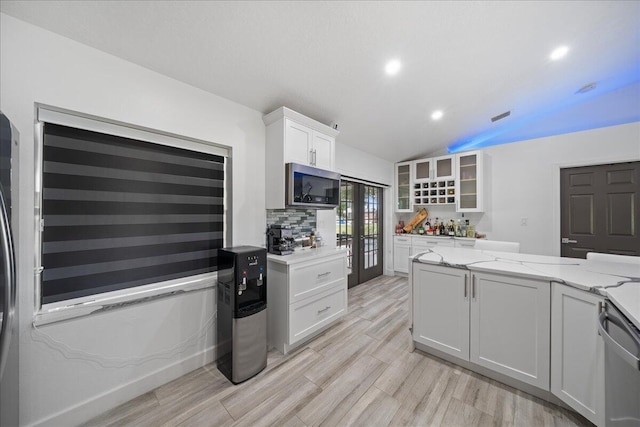 kitchen with light stone counters, white cabinetry, french doors, backsplash, and stainless steel microwave