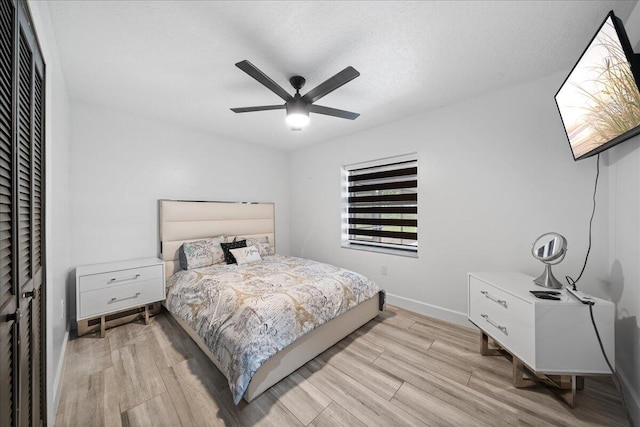 bedroom featuring light wood finished floors, a ceiling fan, baseboards, and a textured ceiling