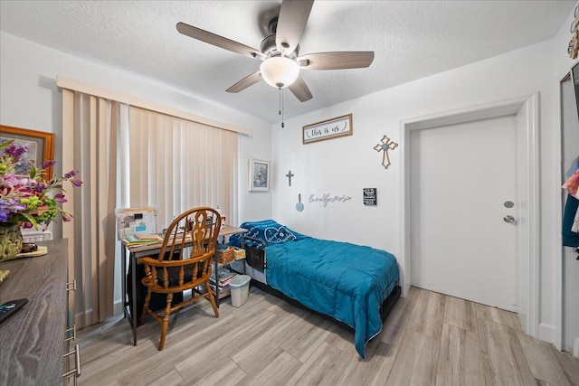 bedroom featuring light wood-style floors, a ceiling fan, and a textured ceiling