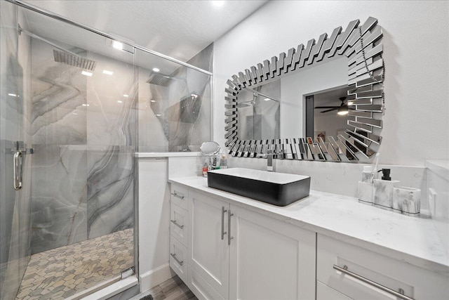 bathroom with ceiling fan, a marble finish shower, wood finished floors, and vanity