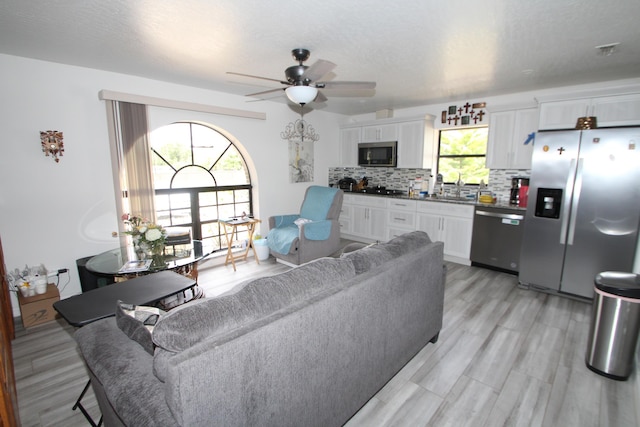 living area with a ceiling fan and light wood-style flooring