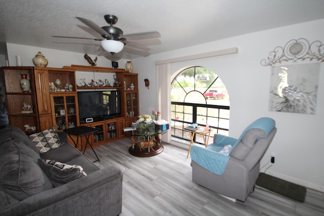 living area with ceiling fan, baseboards, and wood finished floors