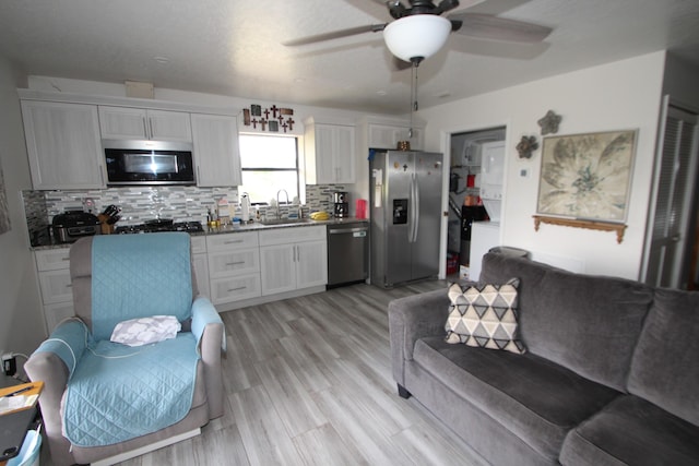 kitchen with appliances with stainless steel finishes, white cabinetry, a sink, and decorative backsplash